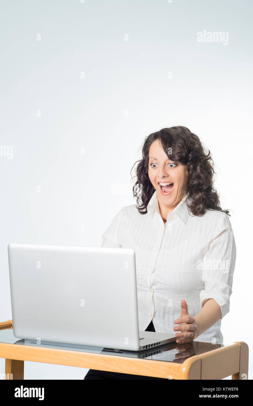 Farbe Fotografie einer jungen Frau mit Überraschung Ausdruck vor einem Laptop Stockfoto