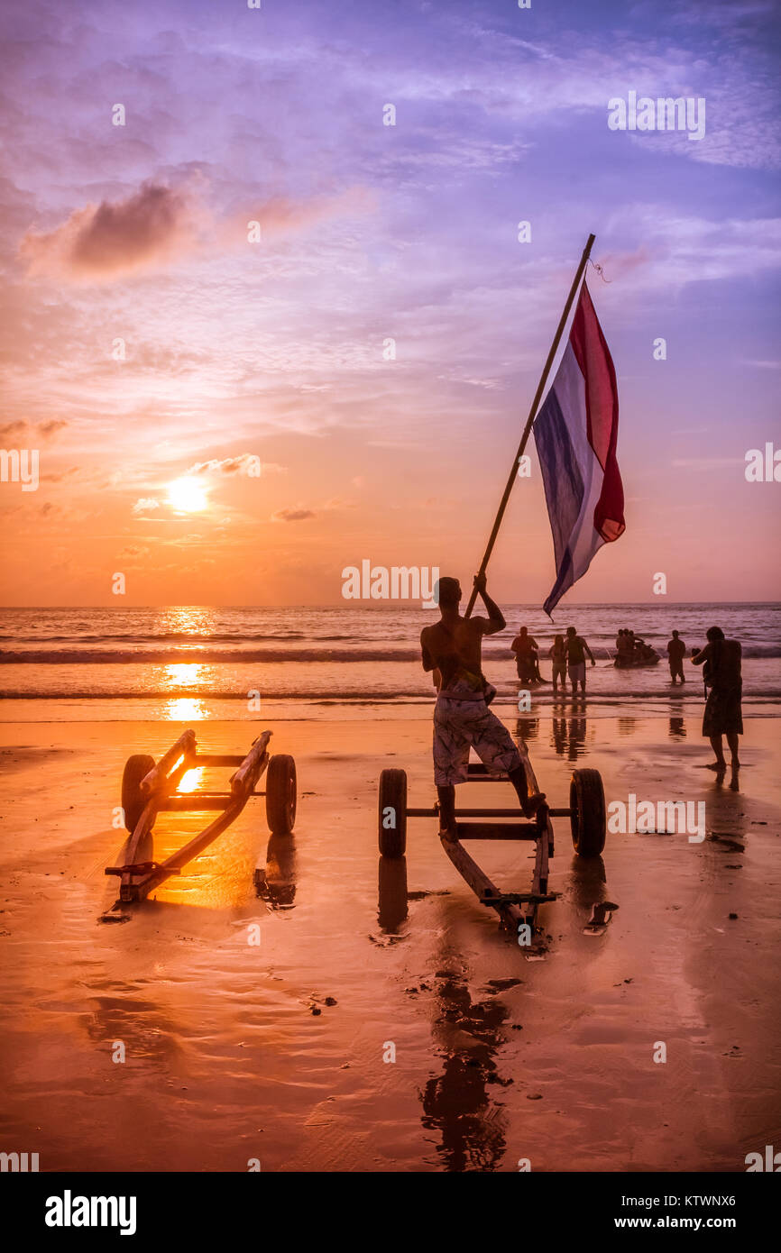 Jetski Fahrer Wellen eine Flagge in Mieter bei Sonnenuntergang zu bringen, Patong Beach, Phuket, Thailand Stockfoto