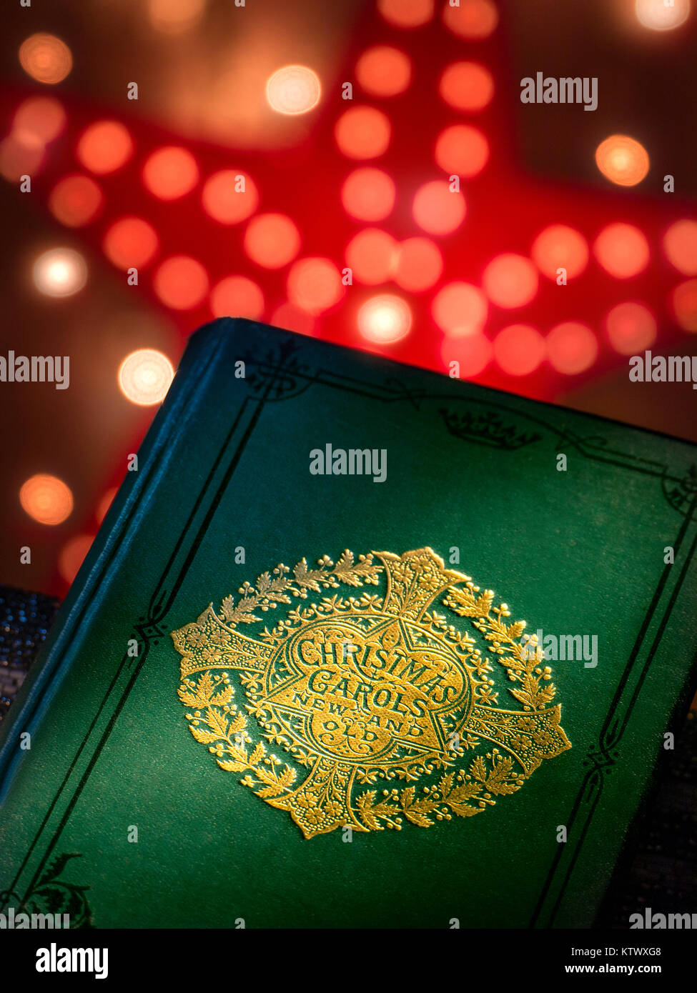 Weihnachtslieder singen „New and Old“-Musikbuchcover mit warmen, einladenden Weihnachtslichtern dahinter. Stockfoto