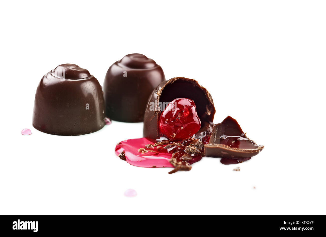 Drei Schokolade Kirschen auf weißem Hintergrund mit Freistellungspfad enthalten. Flache Tiefenschärfe mit selektiven Fokus auf Gebissen por Stockfoto