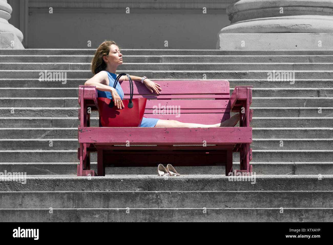 Liegende junge Frau stellt ihr Gesicht zu strahlen der Sonne in einer Stadt Umgebung Stockfoto