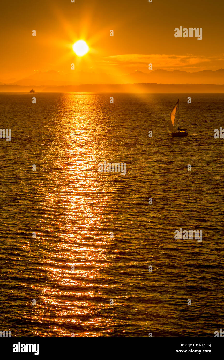 Segelboot und Sonnenuntergang über der Elliott Bay mit Bainbridge Island sichtbar am Horizont von Bell Harbour Marina, Seattle, Washington State, Uni gesehen Stockfoto