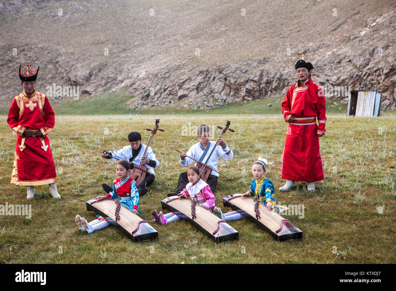 Jungs, Morin khuur (Saiteninstrument) (Pferd - Kopf - Violine) Während junge Mädchen spielen Yatga-Yatuga (Saiteninstrument), Bunkhan, Mongolei, Centr Stockfoto