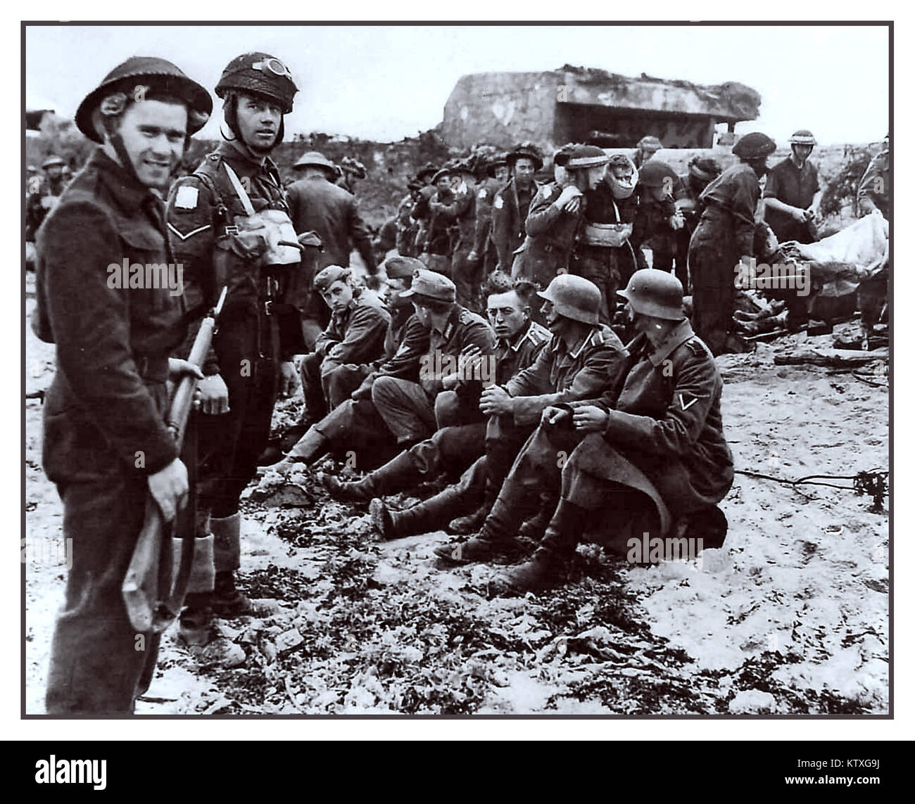 D-Day, 6. Juni 1944 WW2 Normandie deutsche Kriegsgefangene. Britische 5th Bataillon Royal Berkshire Regiment auf Juno Beach Normandie, bewachen Gefangene der Deutschen KRIEGSGEFANGEN des Krieges mit im Hintergrund verletzt zu übergeben Stockfoto