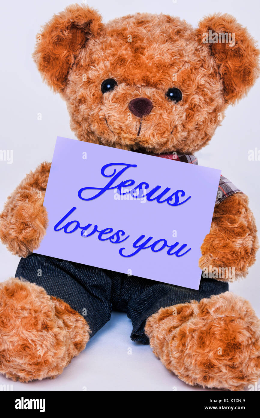 Cute teddy bear Holding ein violettes Schild mit der Aufschrift Jesus liebt Dich auf weißem Hintergrund Stockfoto