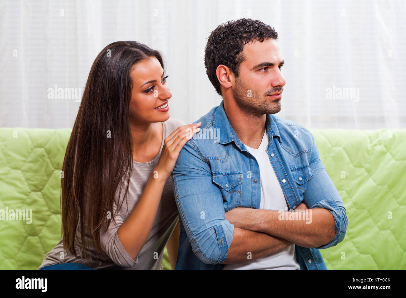 Junges Paar sitzt auf einem Sofa zu Hause. Der Mensch ist wütend. Stockfoto