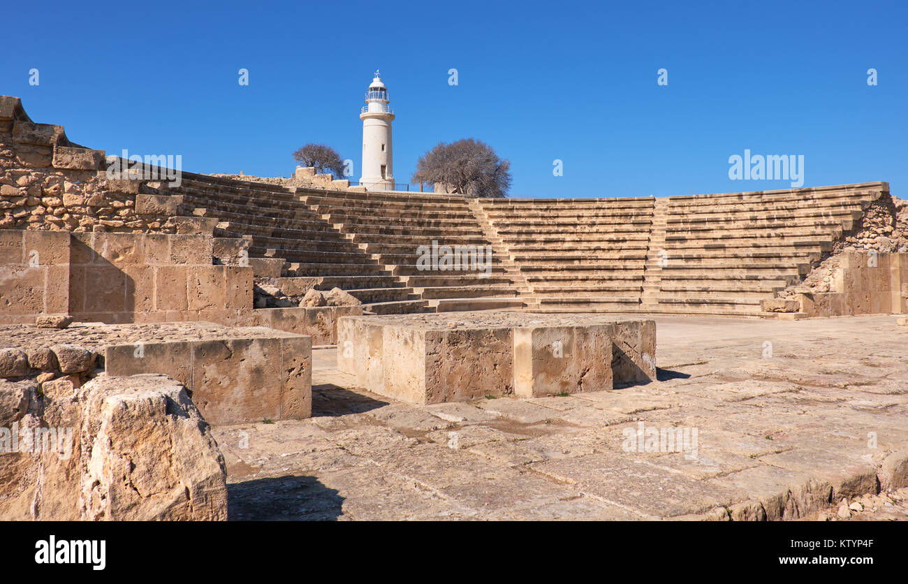 Antike griechische Amphitheater in archäologischen Stätte in Paphos, Zypern, mit einem weißen Leuchtturm auf der Rückseite Stockfoto