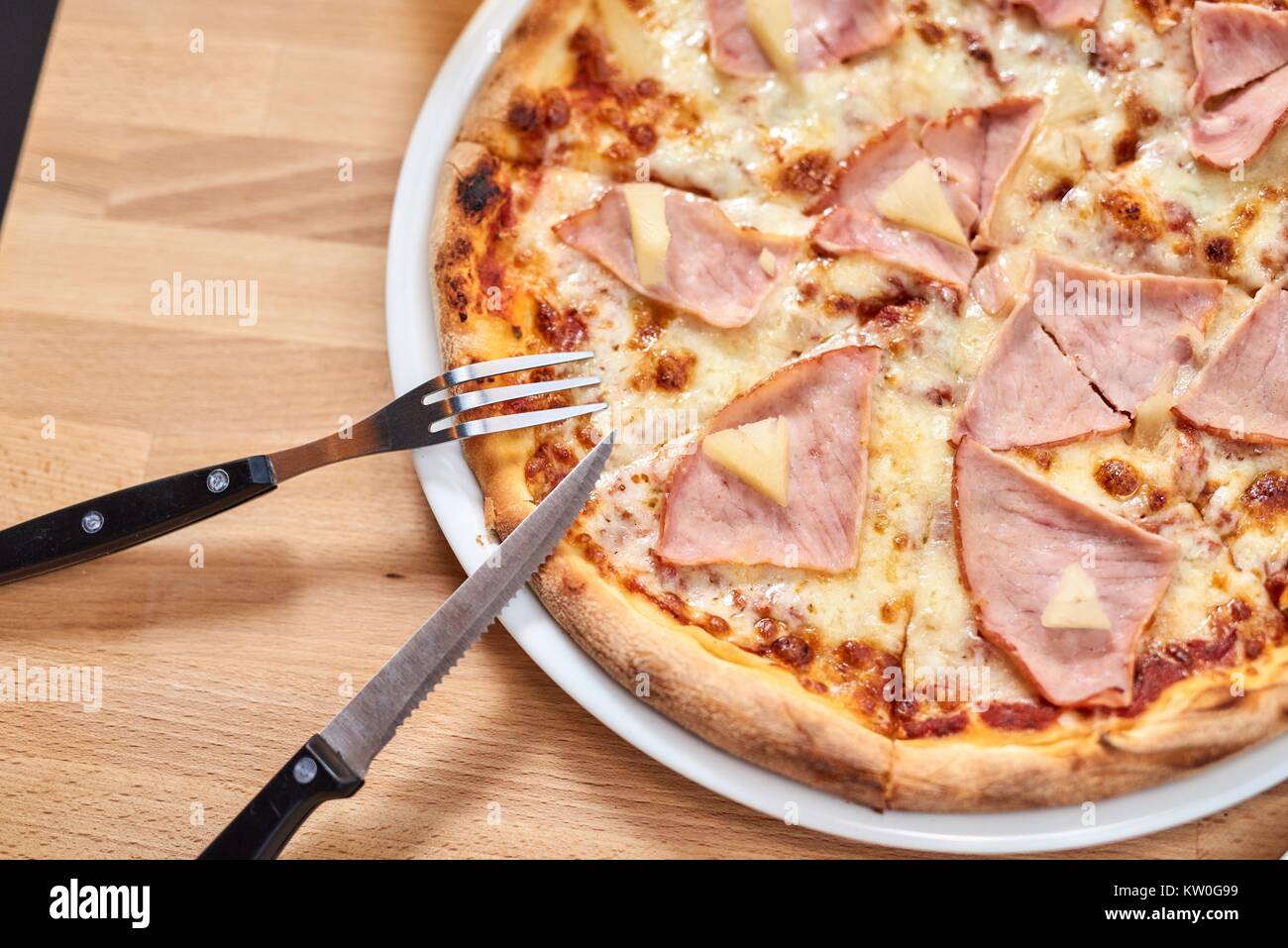 Frische Pizza mit Schinken und Ananas auf hölzernen Tisch im Restaurant. Stockfoto