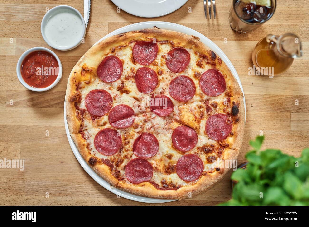 Frische Pizza mit Salami auf hölzernen Tisch im Restaurant. Stockfoto