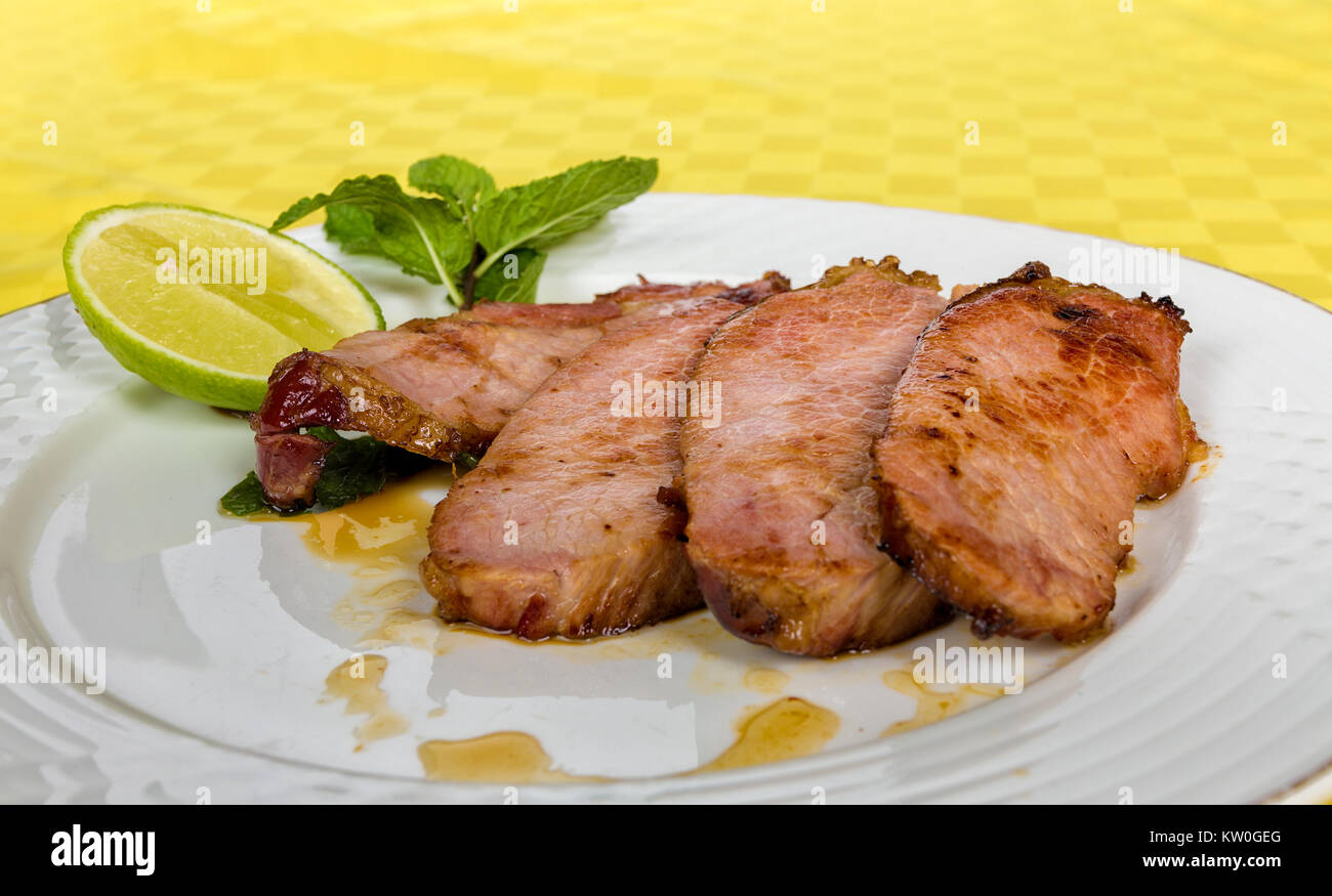 Vier Folie gegrillten geräuchertes Schweinefleisch in einer weißen Schüssel und eine Zitrone Folie serviert. Stockfoto