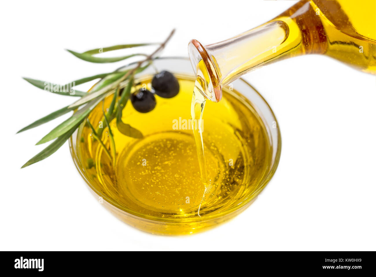 Olivenöl in der Schüssel aus der Flasche und reife Früchte Gießen auf weißem Hintergrund Stockfoto