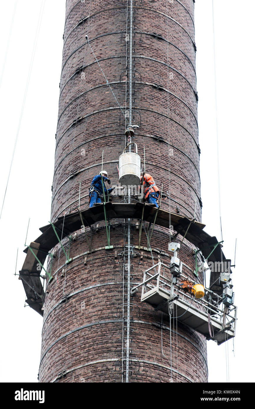 Gerüstbauer bei der Arbeit, eine große Gerüste, Arbeiten in großer Höhe, industrielle Schornstein reparieren. Stockfoto
