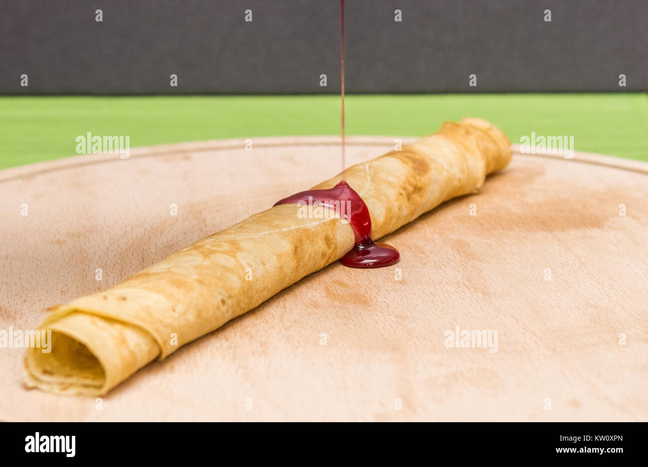 Verschütten Stau auf gerollt Krepp, russische blini auf einer hölzernen Schneidebrett Stockfoto