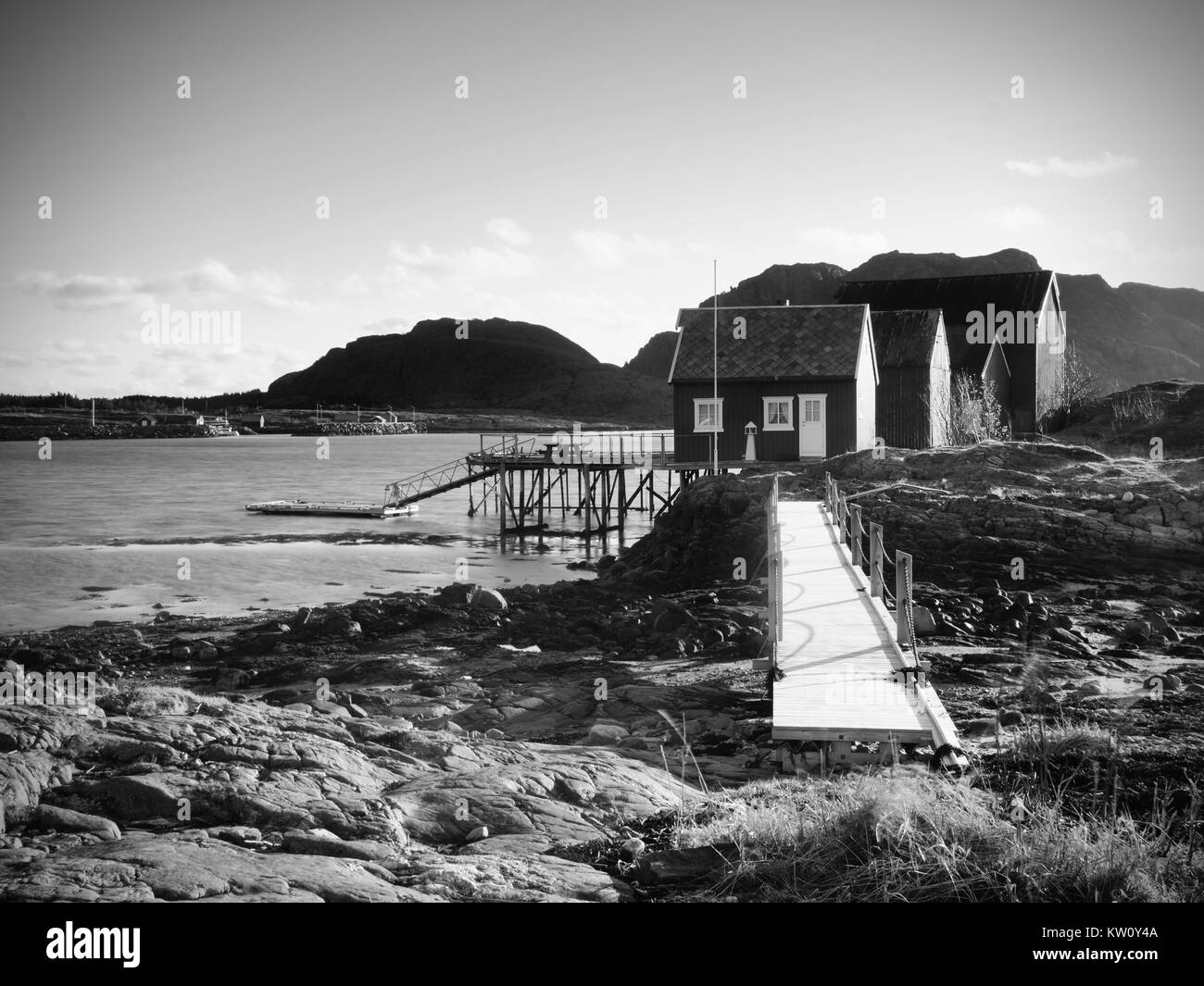 Norwegen Fischerdorf auf steinigen Insel. Shinning rot weißen Häusern in einer ruhigen Bucht. Glatte Wasser spiegeln klar cyan Himmel. Stockfoto