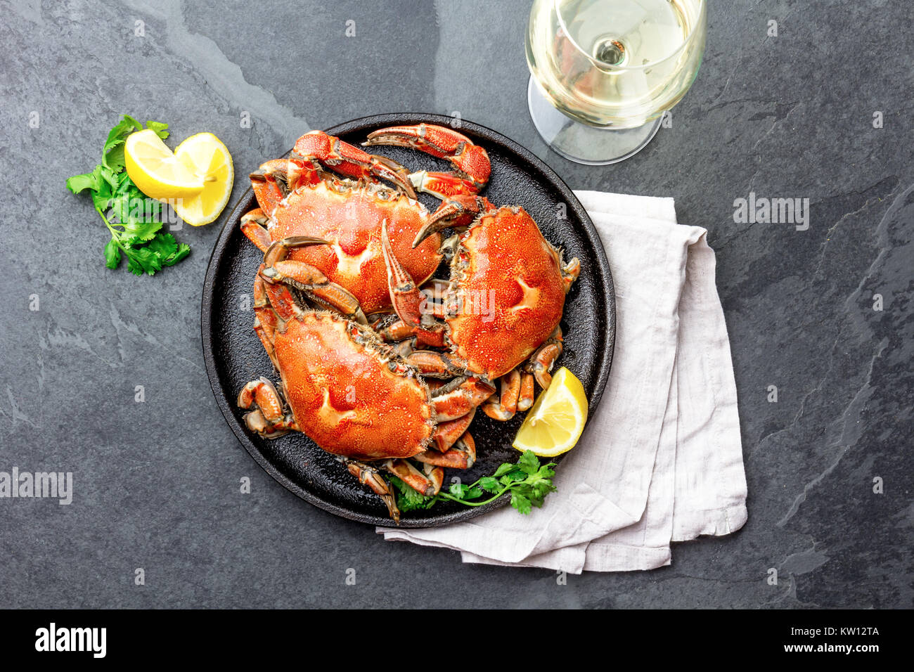 Gekochte Krabben auf dem schwarzen Schild mit weißem Wein serviert, schwarzer Schiefer Hintergrund, Ansicht von oben. Stockfoto