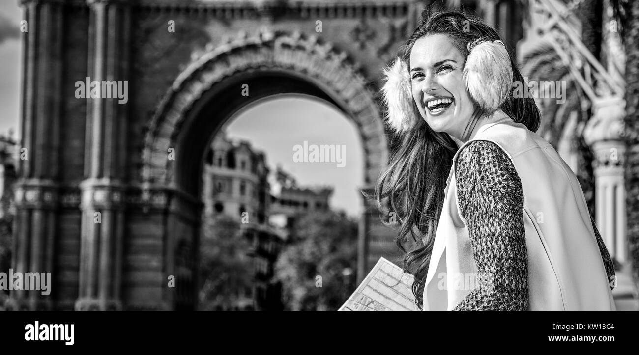 in Barcelona für einen perfekten Winter. lächelnd elegante Frau in Ohrenschützer in der Nähe von Arc de Triomf in Barcelona, Spanien mit Blick in die Ferne Karte Stockfoto