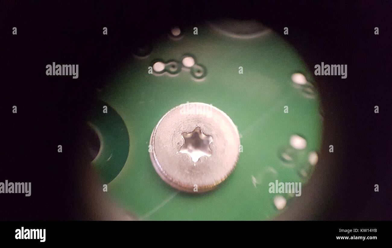 Lichtmikroskopische Aufnahme bei ca. 30-facher Vergrößerung mit einer Schraube am Festplattenlaufwerk auf der Querseite einer Leiterplatte (PCB), 2016. Stockfoto