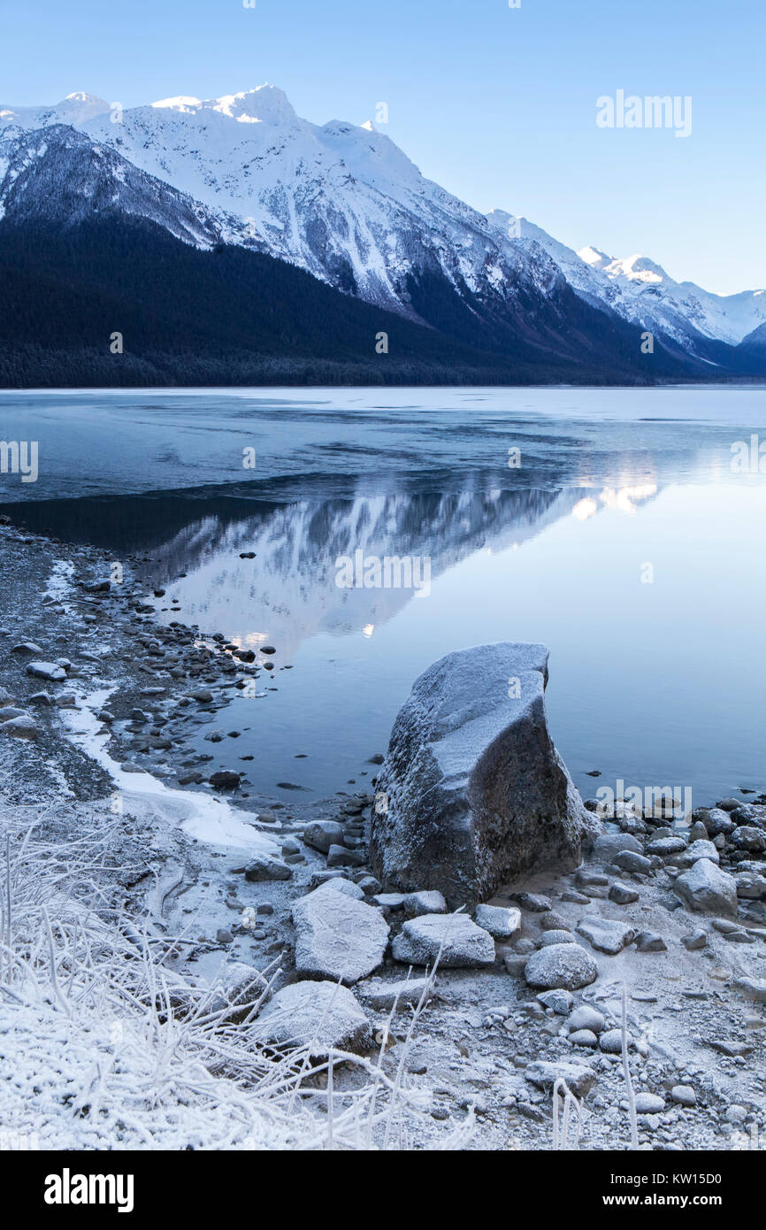 Chilkat See mit Vereisung auf Open Water mit Bergen im Hintergrund spiegelt sich auf einen klaren Wintertag. Stockfoto