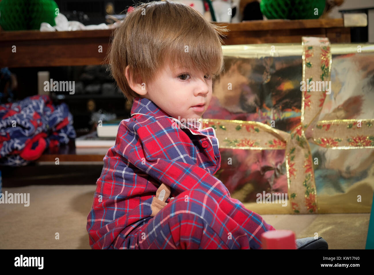 Kleinkind saß auf dem Boden in seinem Schlafanzug mit Spielzeug spielen am Weihnachtsmorgen Stockfoto