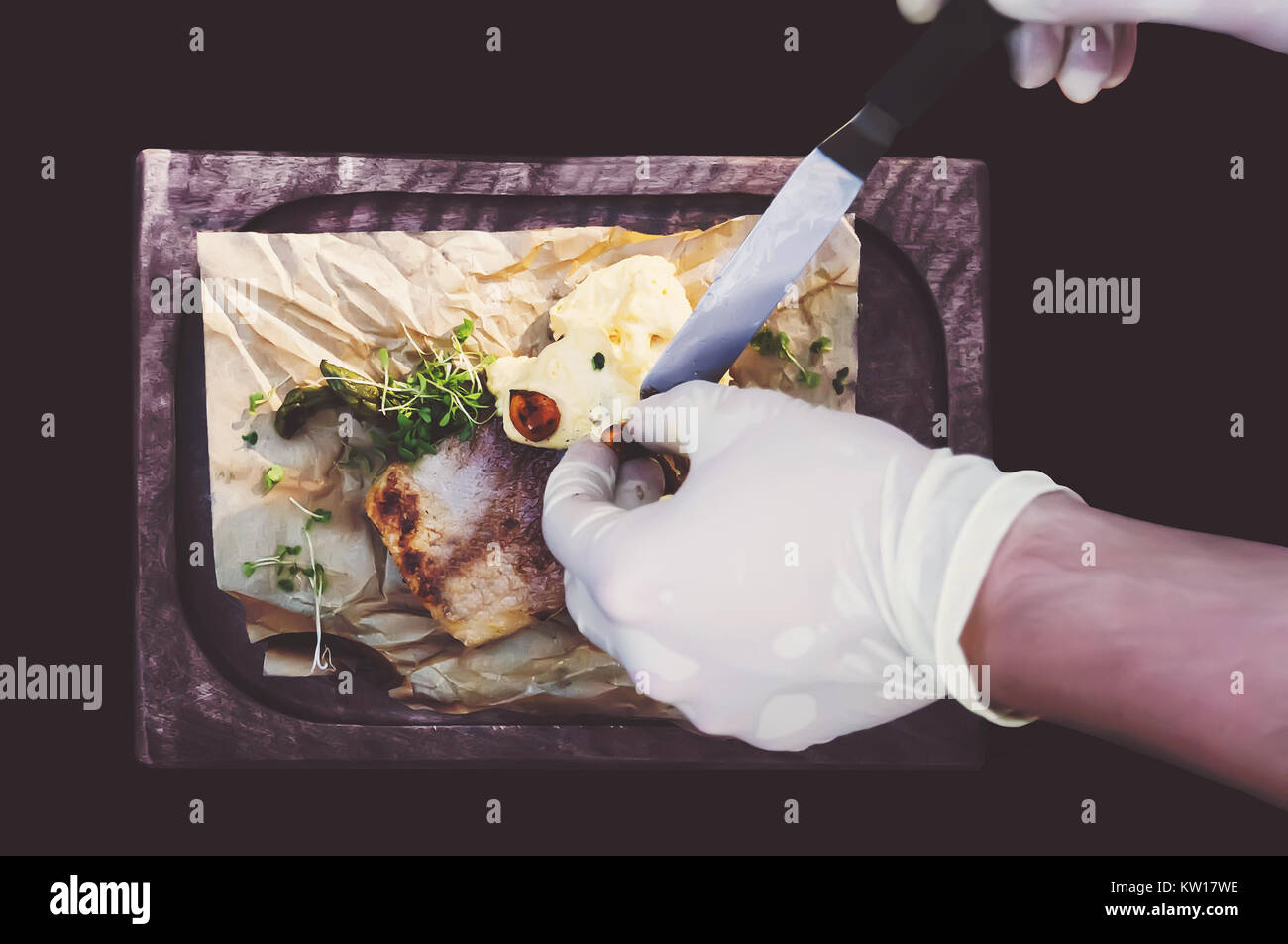 Prozess der Küche Fisch. Hände Köche in saubere, weiße Handschuhe setzt eine Sauce zu gegrilltem Fisch. Die Aussicht von oben. Stockfoto