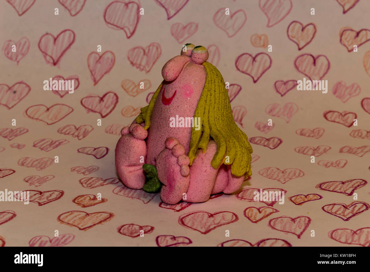 Valentinstag. Comic Figur eines Mädchens aus Teig und Salz. Vor dem Hintergrund der rot gezeichnet Bleistift Herzen. Stockfoto