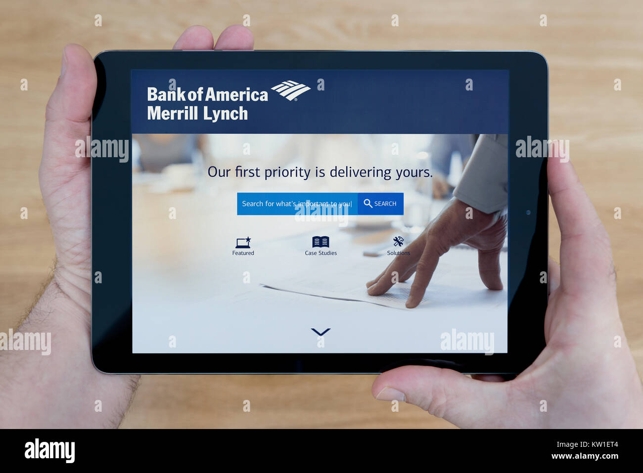 Ein Mann schaut auf die Merrill Lynch Wealth Management Website auf seinem iPad tablet device, Schuß gegen einen hölzernen Tisch top Hintergrund (nur redaktionelle Nutzung) Stockfoto