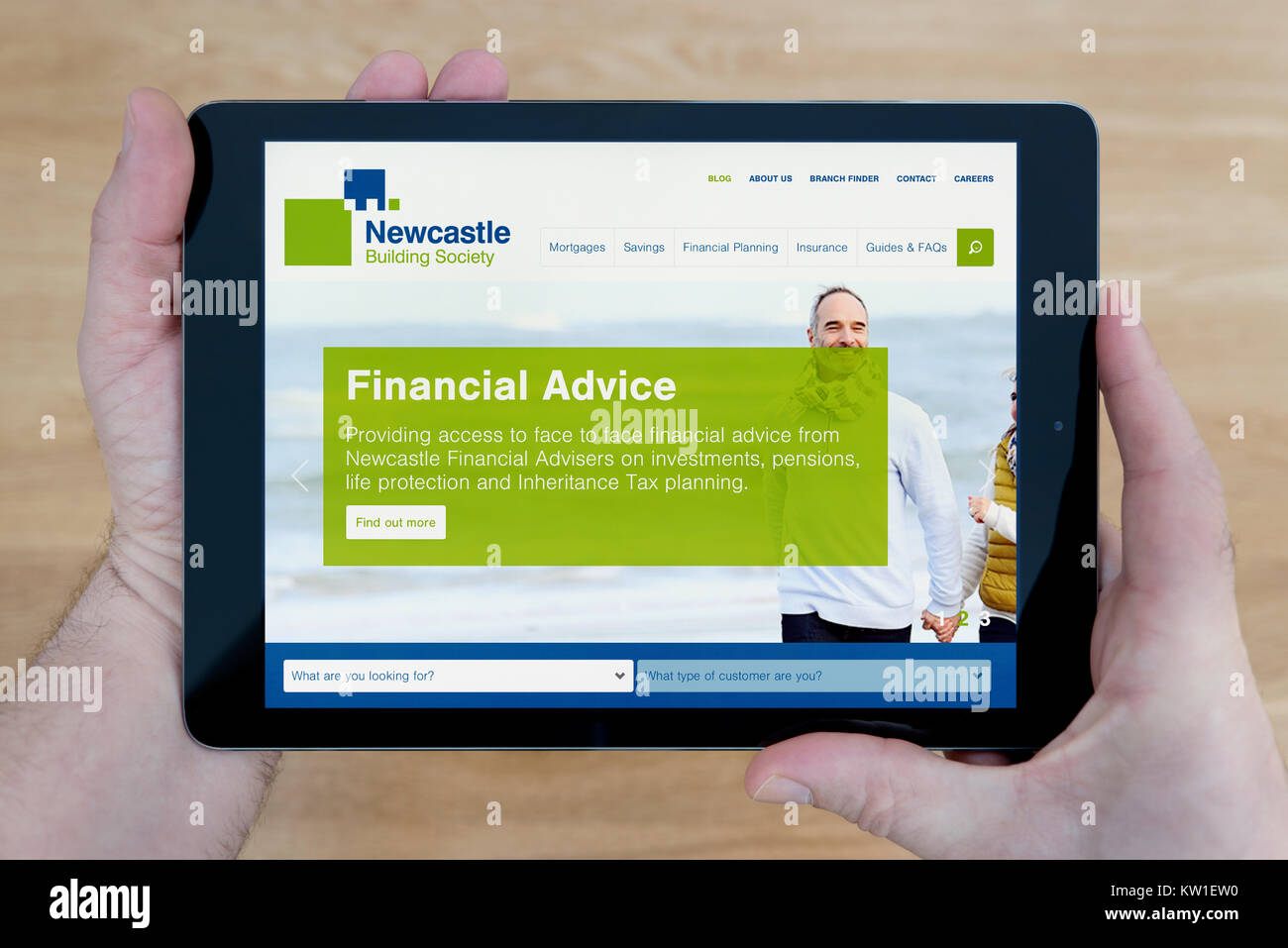 Ein Mann schaut auf die Newcastle Building Society Website auf seinem iPad tablet device, Schuß gegen einen hölzernen Tisch top Hintergrund (nur redaktionelle Nutzung) Stockfoto