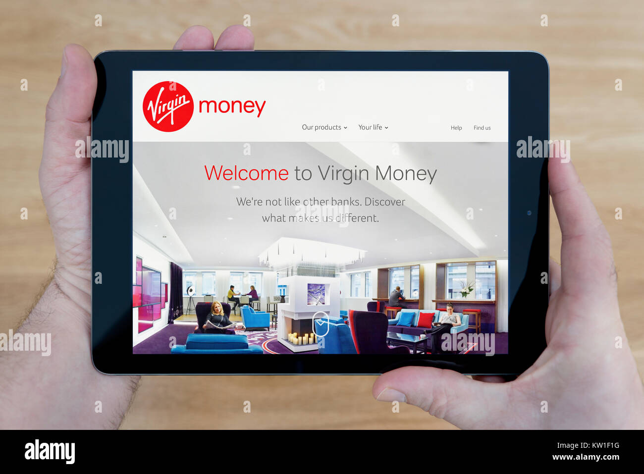 Ein Mann schaut auf die Virgin Money Website auf seinem iPad tablet device, Schuß gegen einen hölzernen Tisch top Hintergrund (nur redaktionelle Nutzung) Stockfoto