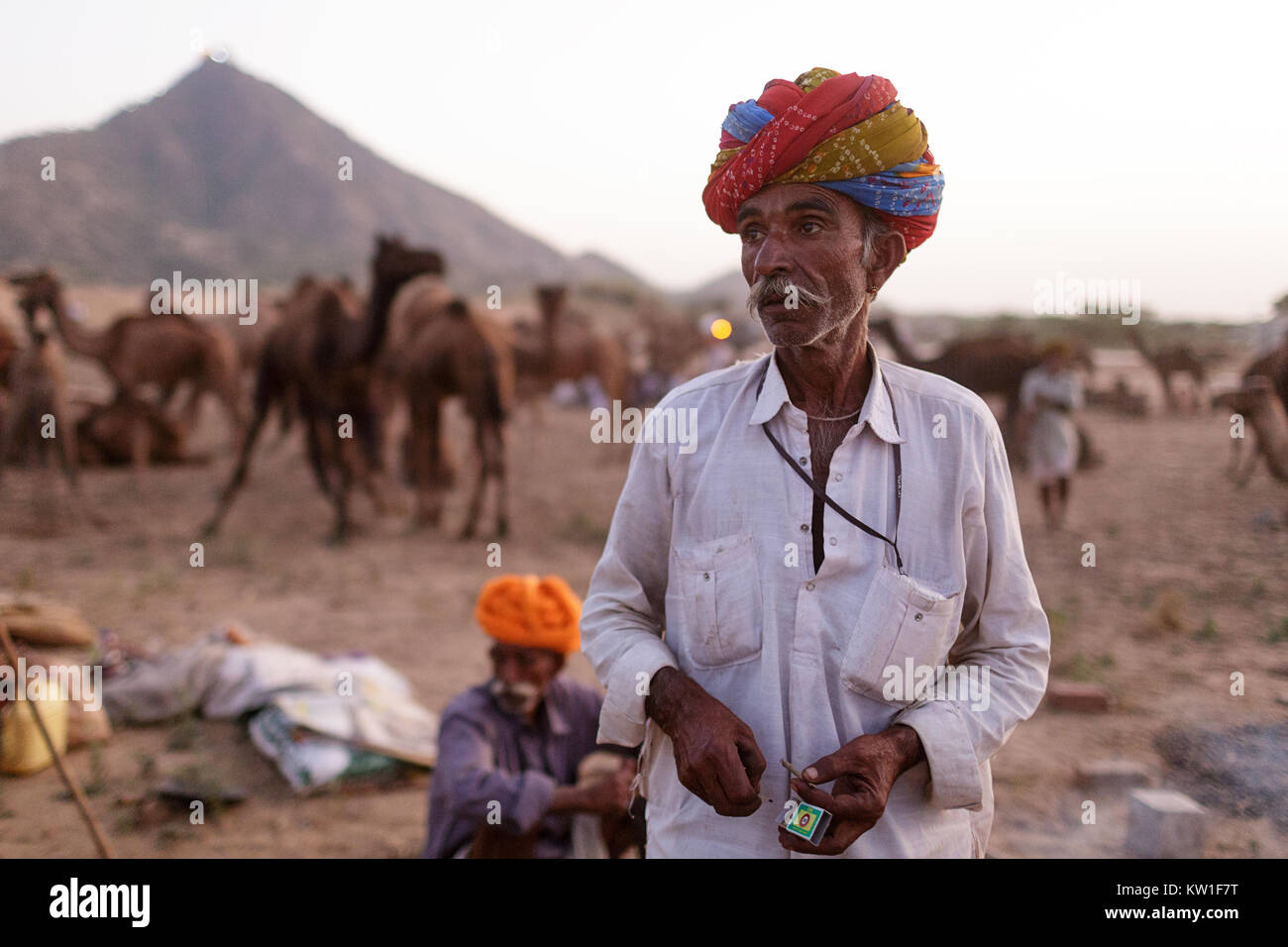 Szene in Pushkar Camel Fair, Trader tragen turban Beleuchtung Feuer in der Dämmerung, Pushkar, Rajasthan, Indien Stockfoto