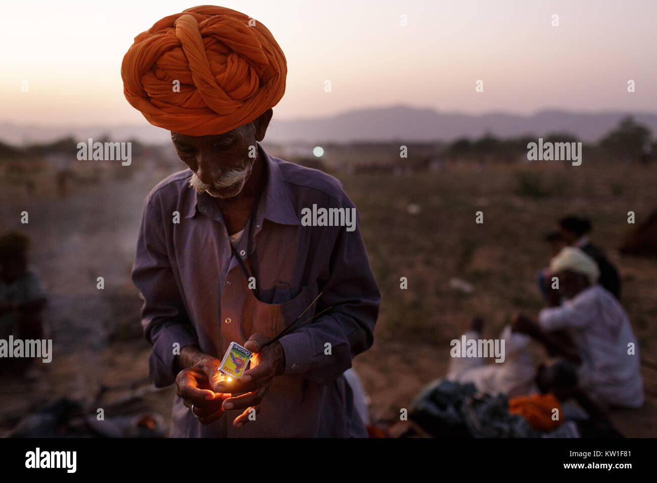 Szene in Pushkar Camel Fair, Trader tragen turban Beleuchtung Feuer in der Dämmerung, Pushkar, Rajasthan, Indien Stockfoto