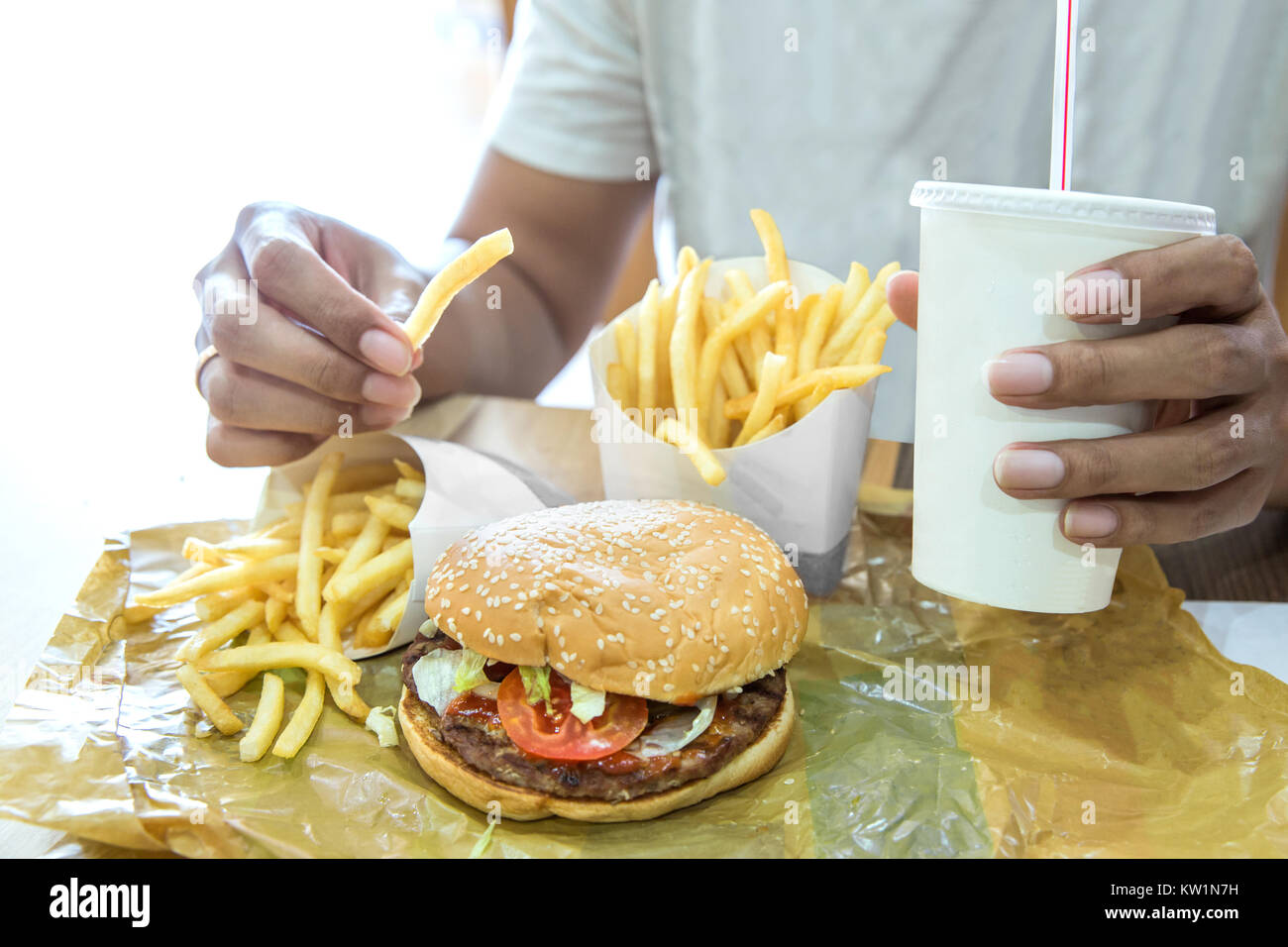 Mann mit einem Hamburger in einem Fast-Food-Restaurant Stockfoto