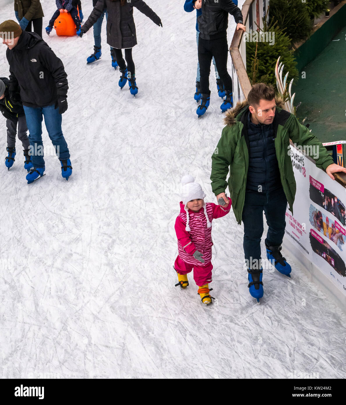 Edinburgh, Schottland, Großbritannien, 30. Dezember 2018. Familien mit kleinen Kindern genießen das Neujahrswochenende Schlittschuhlaufen auf dem St. Andrew Square. Ein Vater hält die Hand eines kleinen Mädchens, während sie Schlittschuhe führt Stockfoto
