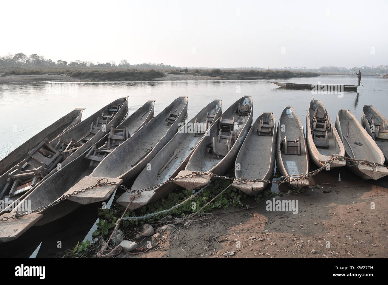 Eine Reihe von alten Vintage hölzerne Boote stehen am Ufer des Flusses von Ketten aus Metall, im Hintergrund das gegenüberliegende Ufer gebunden. Stockfoto