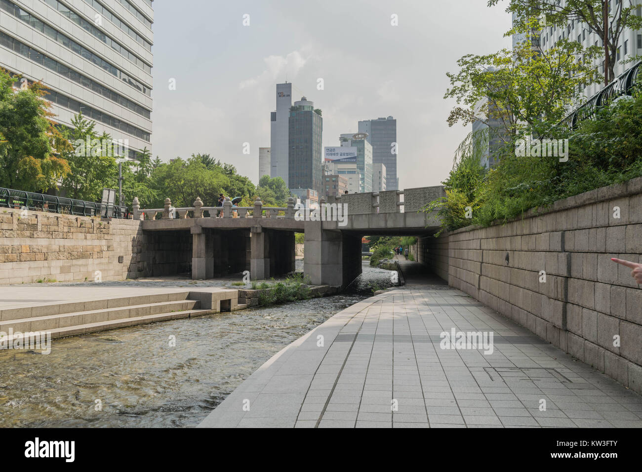 Eines der konkreten Brücken über den Cheonggyecheon Strom und Fußgängerweg, mit modernen Hochhäusern im Hintergrund, in Seoul, Südkorea Stockfoto