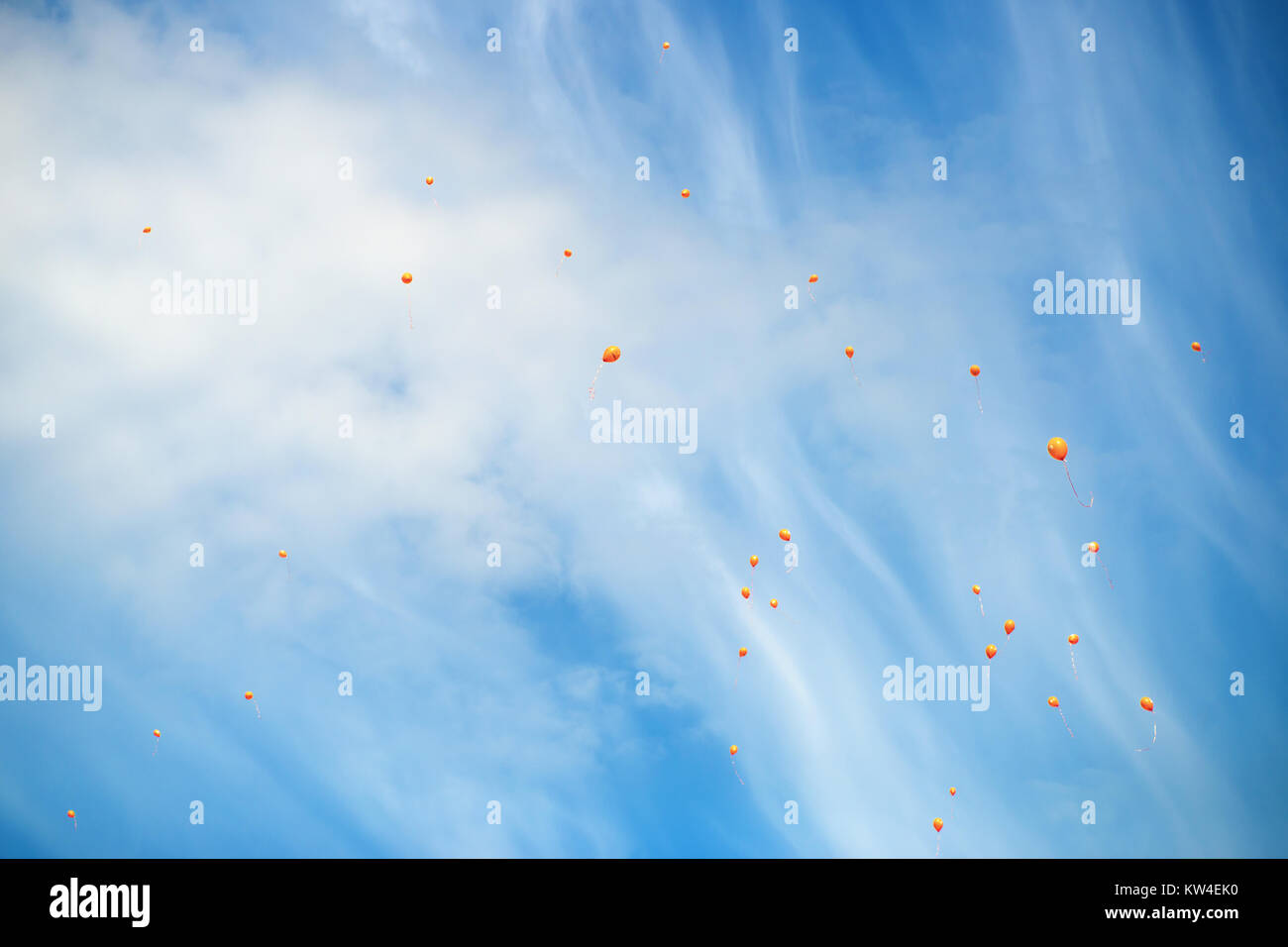 Orange Ballons auf einem blauen Himmel mit weißen Wolken Stockfoto