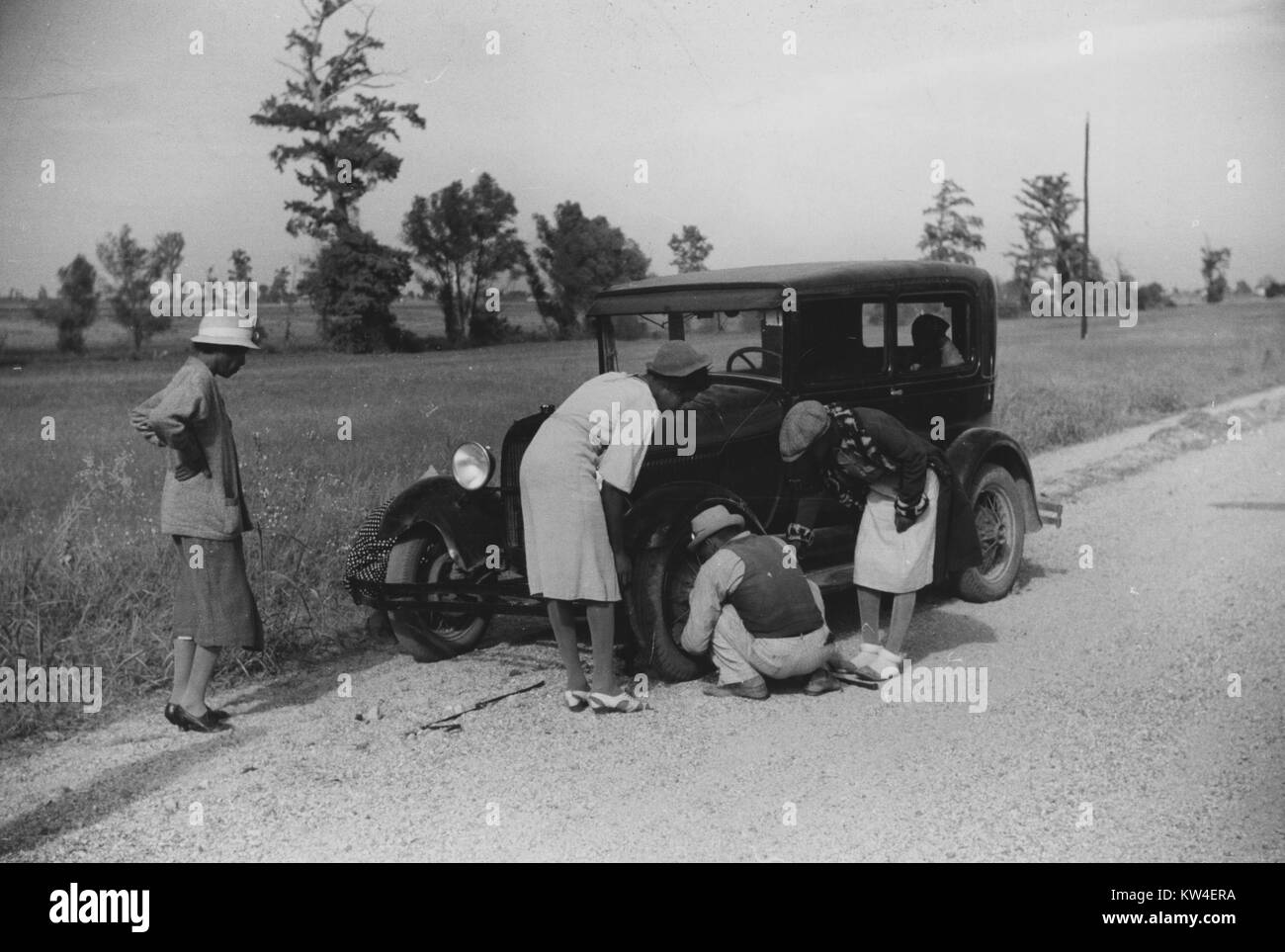 Eine Gruppe von Männern und Frauen, Reiten in einem Auto versuchen, einen Reifen auf eine Straße in der Nähe der Knowlton Plantage in Perthshire, Mississippi Delta, Mississippi, Oktober, 1939 zu reparieren waren. Stockfoto