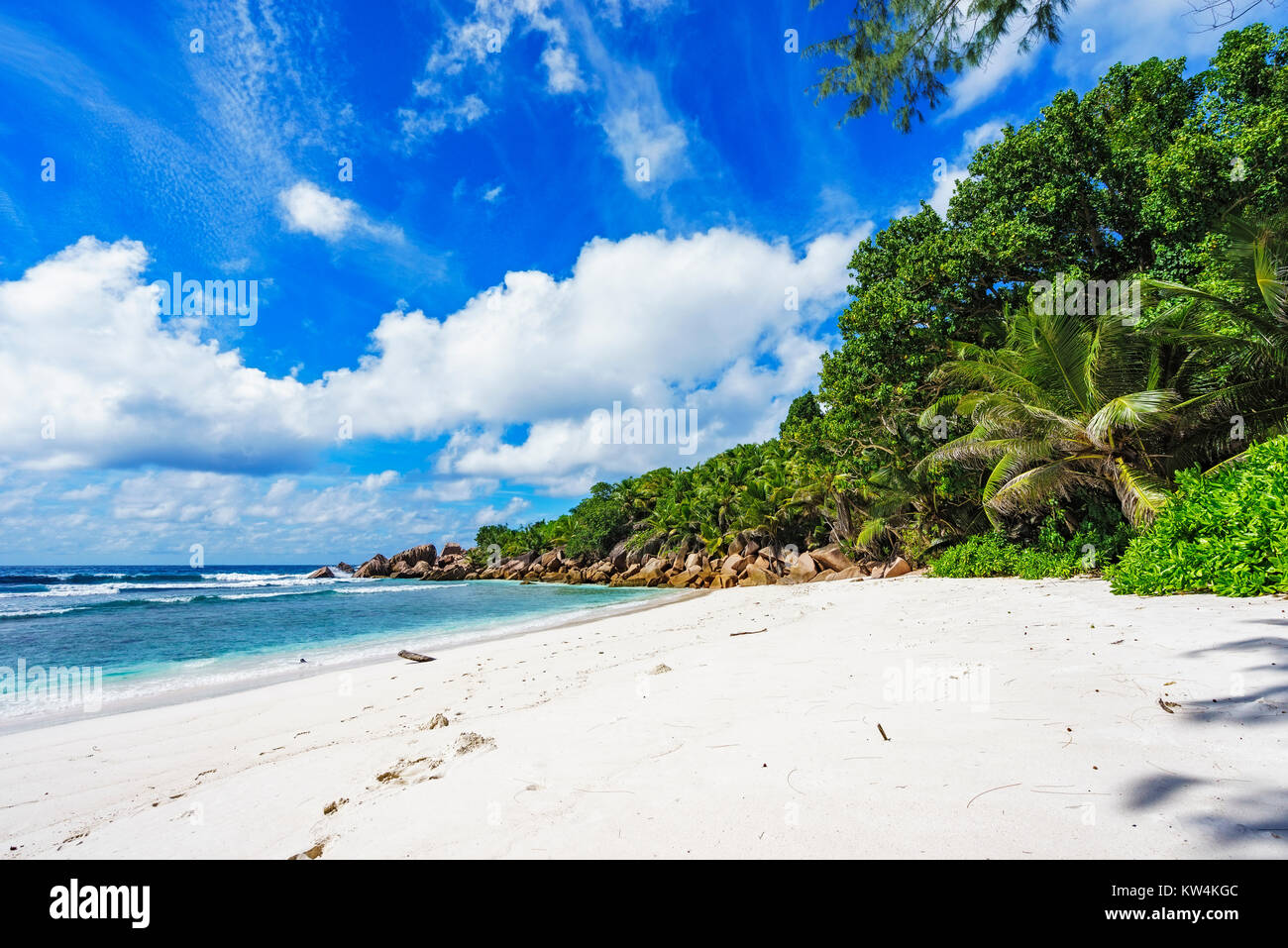 Granitfelsen, weißer Sand, türkises Wasser, blauer Himmel und Palmen am Paradise Beach auf den Seychellen Anse Cocos, La Digue Stockfoto