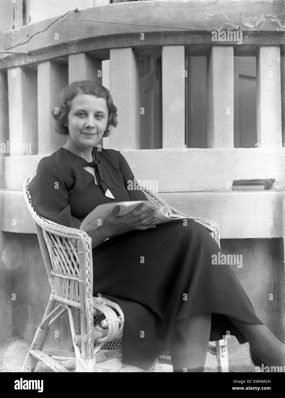 Portrait einer jungen, hübschen Frau sitzt in einem Korbstuhl im Freien und das Lesen einer Zeitschrift, Ungarn, 1929. Von einem Gelatine Prozess Glasplatte negative digitalisiert. Stockfoto