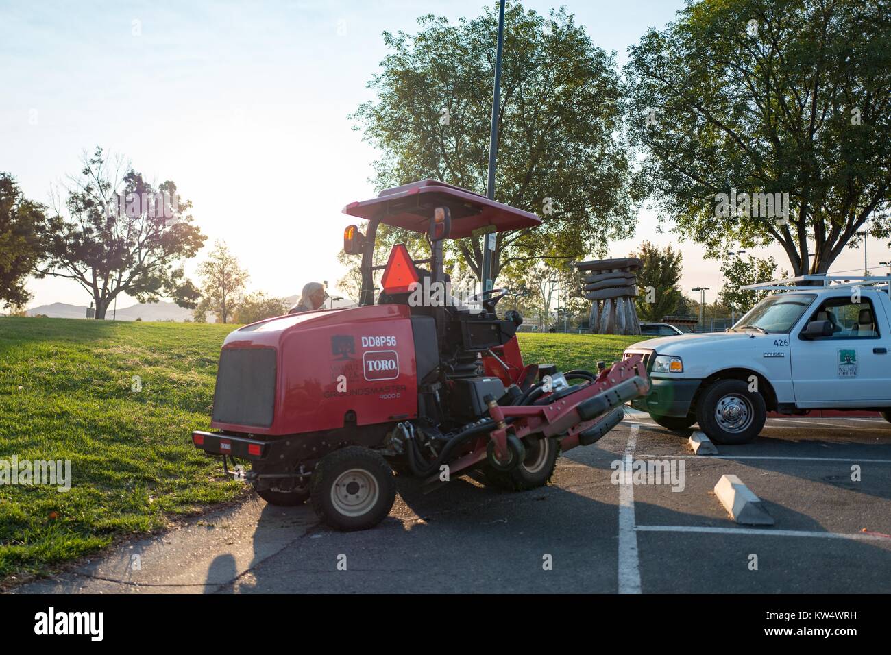 Rote Toro Traktor im Morgengrauen in den öffentlichen Park in Walnut Creek, Kalifornien, mit dem Gras mähen Anlage ausgestattet, 19. September 2016. Stockfoto