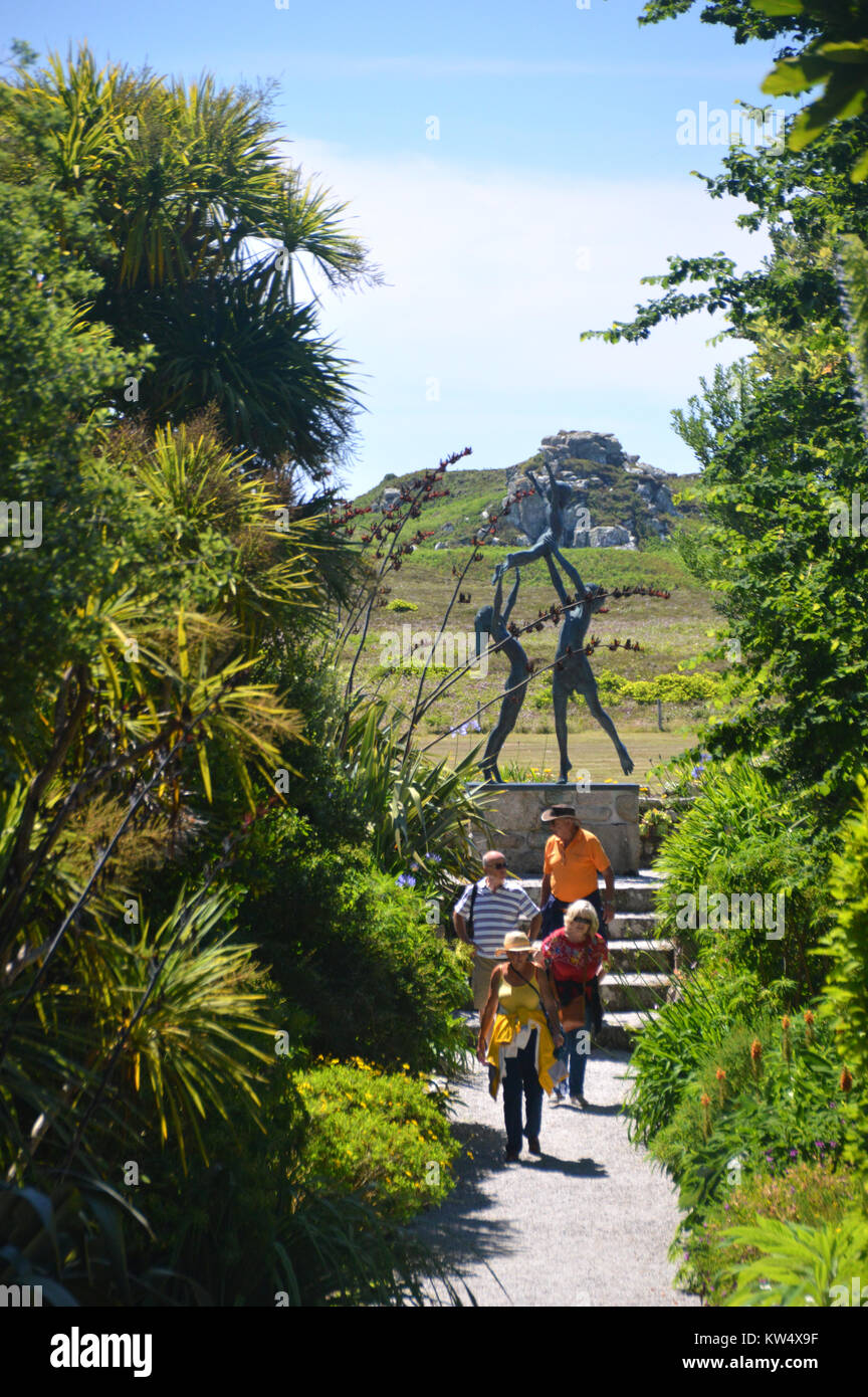 Vier Leute auf den Leuchtturm zu Fuß von der Skulptur der Drei Kinder beim Spielen in Tresco Abbey Gardens, Tresco, Isles of Scilly, Cornwall, Großbritannien Stockfoto
