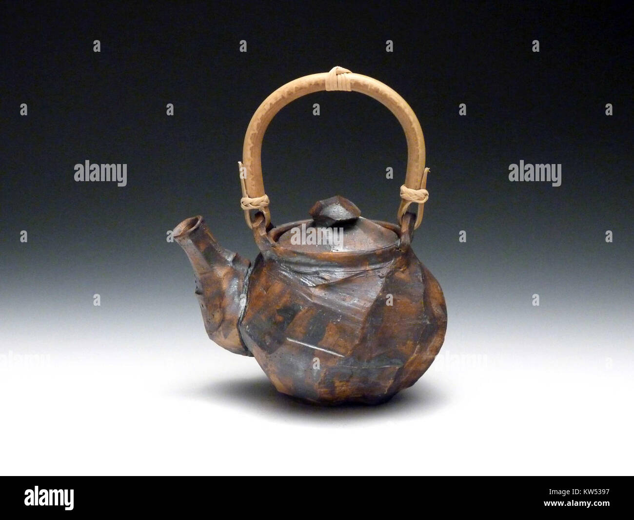 Diese Teekanne verfügt über eine auffällige schwarze Glasur und einen Bambusgriff, der elegante Handwerkskunst mit funktionellem Design verbindet. Die geometrischen Facetten der Teekanne betonen eine moderne Ästhetik, während der Bambusgriff dem Stück eine natürliche Note verleiht und sie zu einer beliebten Wahl für den praktischen Gebrauch und die Präsentation macht. Stockfoto