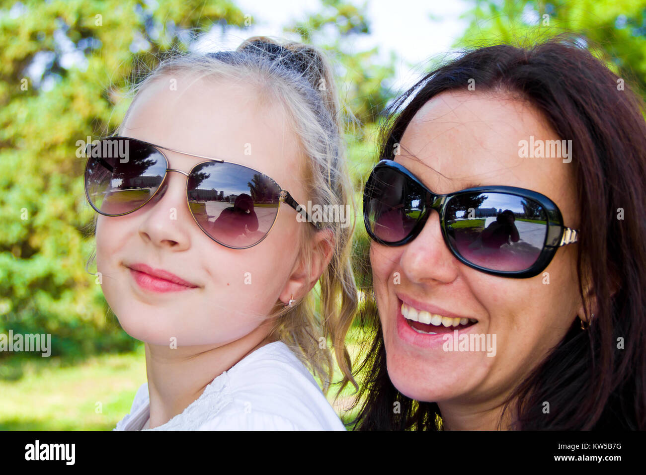 Foto von lächelnden Mutter und Tochter in Sonnenbrillen Stockfoto