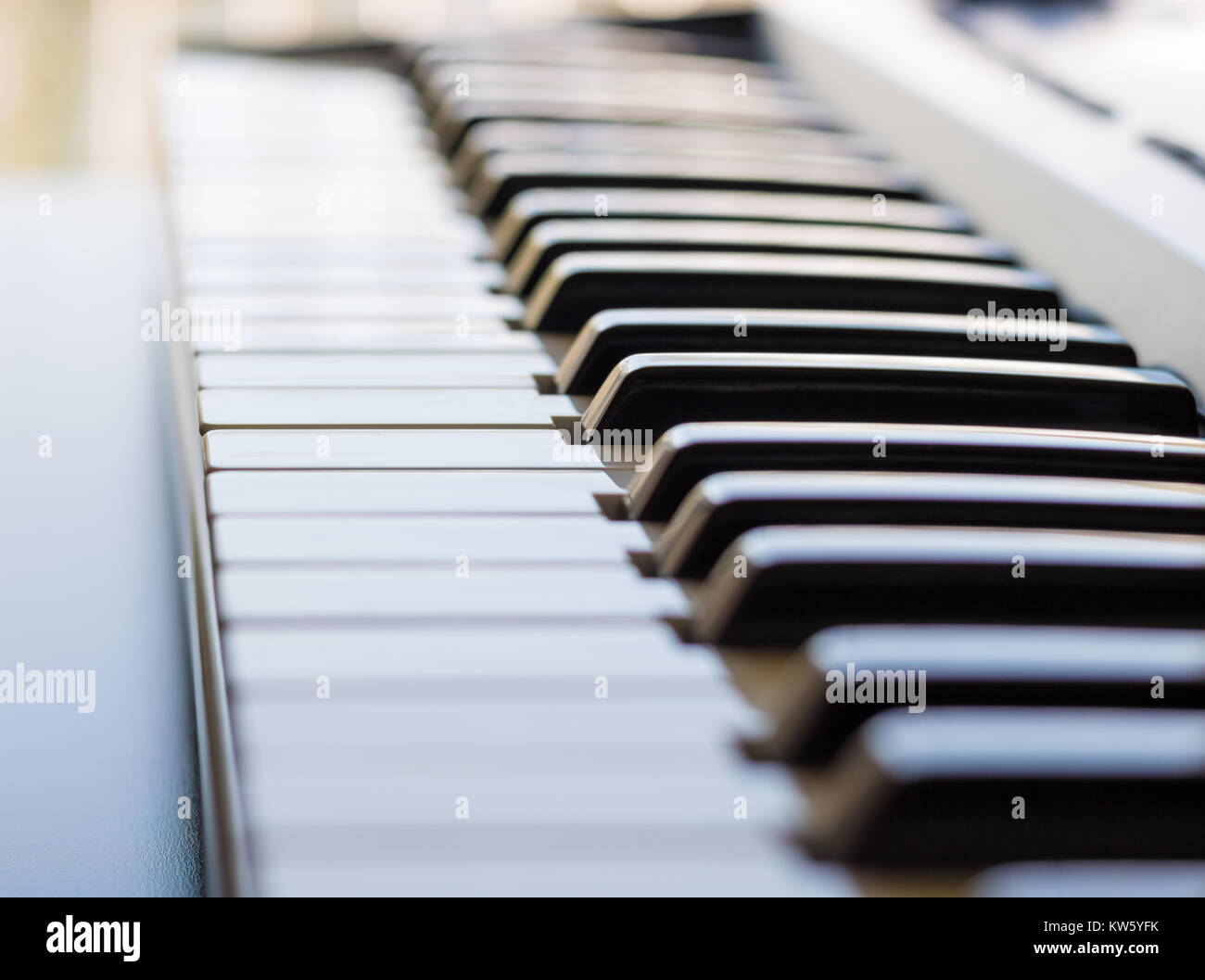 Eine elektronische Tastatur wird in einem hellen Raum neben einem offenen Fenster. Dies ist ein helles Bild mit dem Fokus auf der Tastatur ivory Keys. Stockfoto