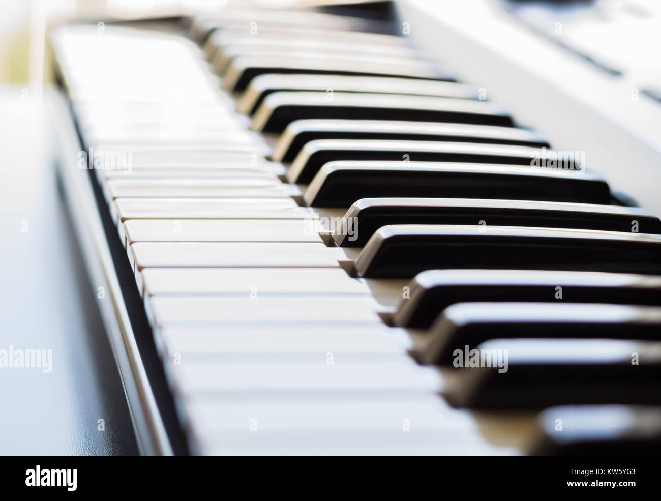 Eine elektronische Tastatur wird in einem hellen Raum neben einem offenen Fenster. Dies ist ein helles Bild mit dem Fokus auf der Tastatur ivory Keys. Stockfoto