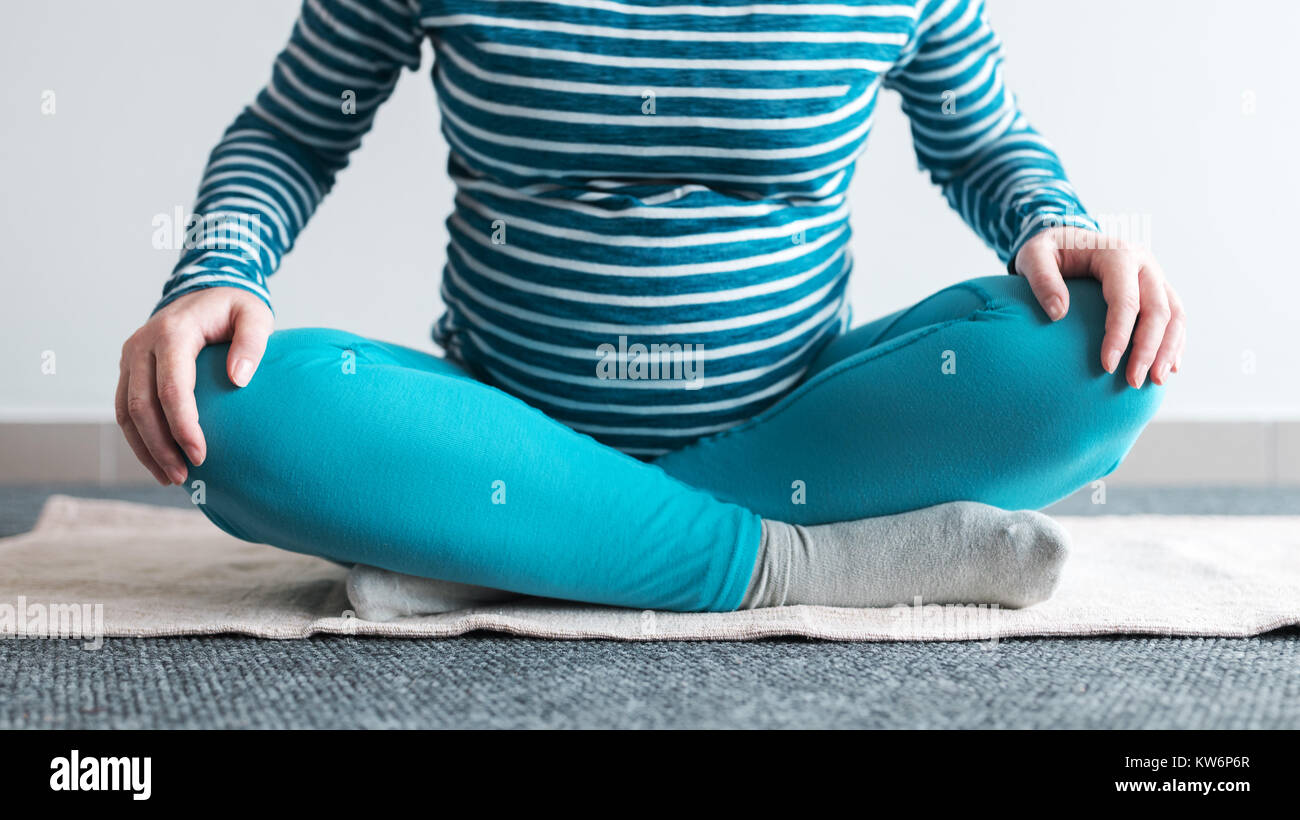 Schwangeren Yoga Übung zu Hause. Schwangerschaft Yoga und drinnen Fitness Concept. Unbenotete kontrastarmen Aufnahmen mit natürlichen Fenster Licht. Stockfoto