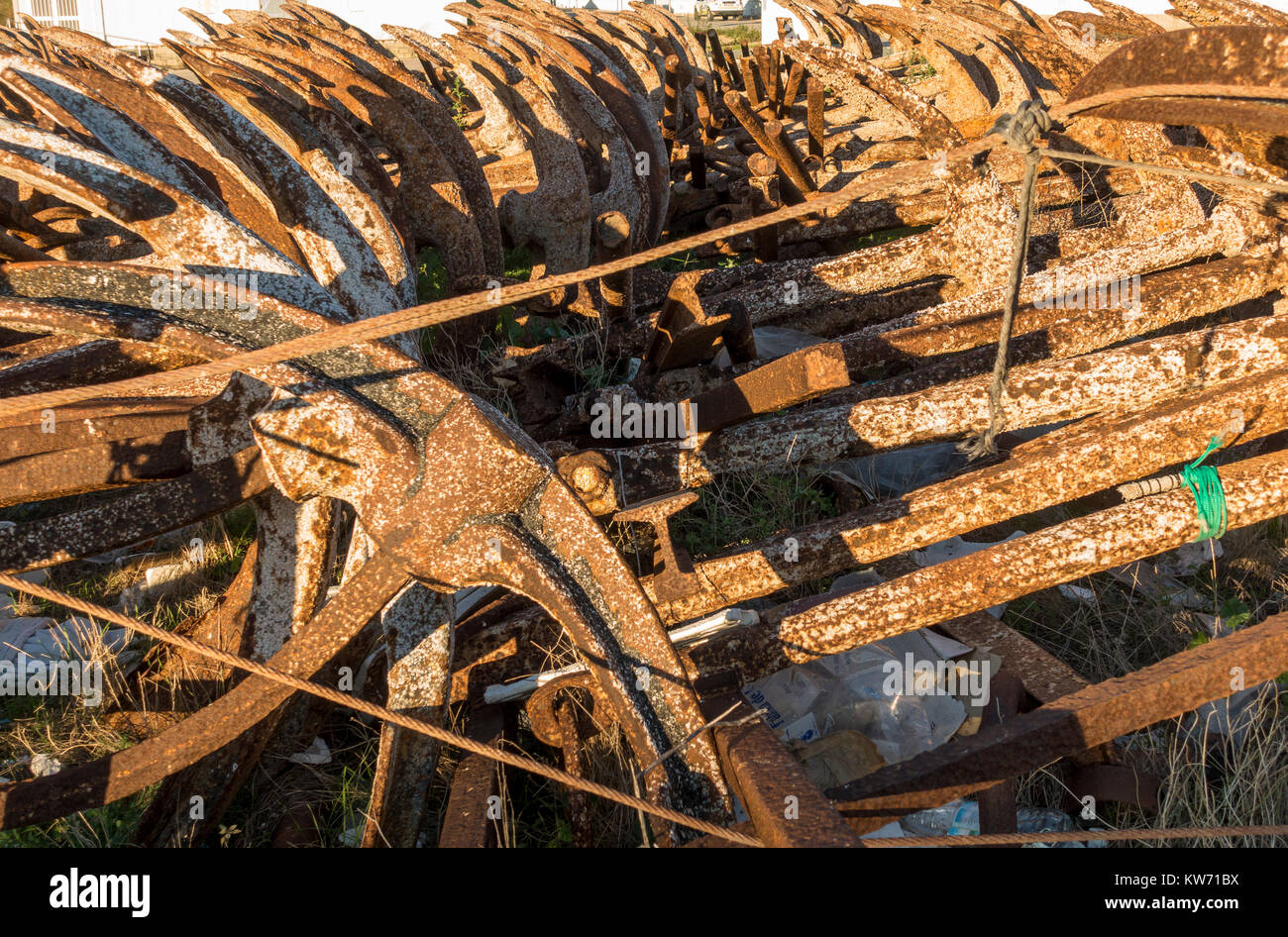 Rostiger Anker, für den Thunfischfang eingesetzt, außerhalb der Saison auf trockenem Land gestapelt im Hafen von Barbate, Costa de la Luz, Andalusien, Spanien. Stockfoto
