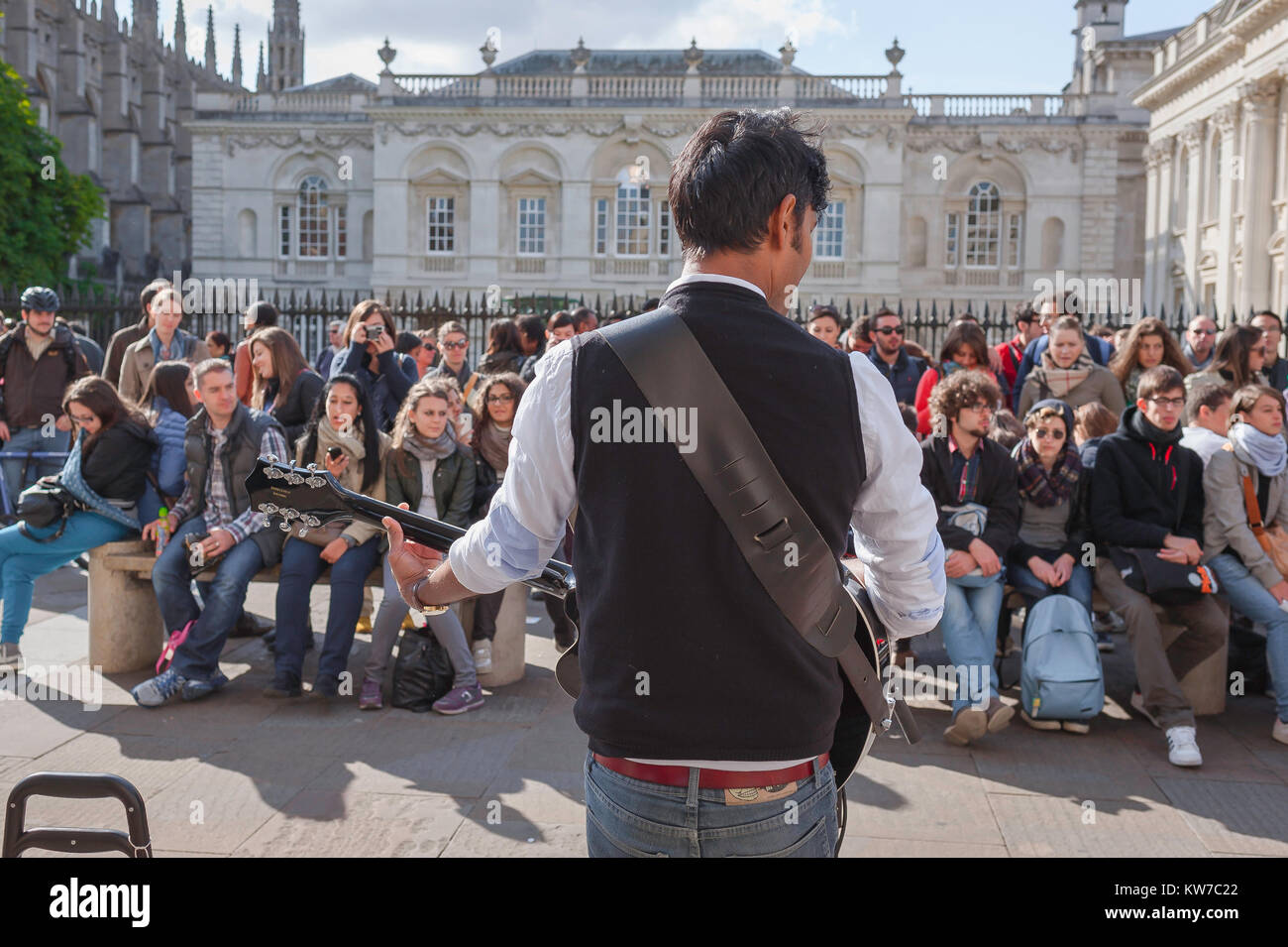 Busker street UK, Rückansicht eines Gaukler unterhalten eine Schar junger Menschen in King's Parade im Zentrum von Cambridge, England. Stockfoto