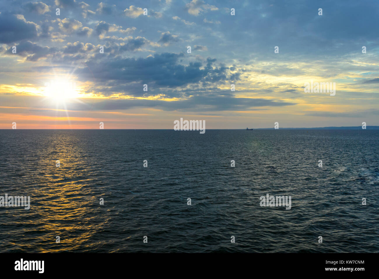 Malerische Meer Landschaft - die Sonne über dem Meer gegen einen bewölkten Himmel und in der Ferne können Sie das Schiff und Land sehen. Stockfoto