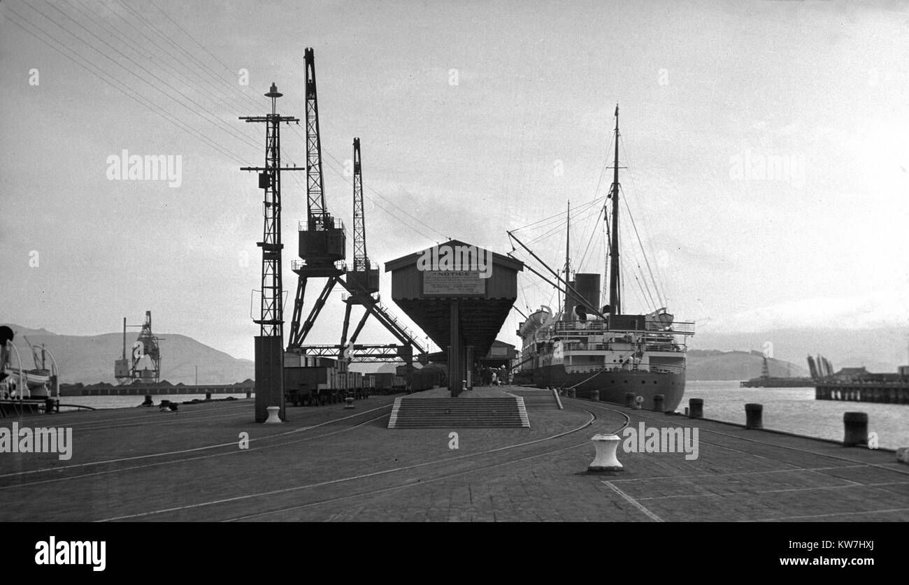 Schiffe laden am Hafen von Lyttleton, in der Nähe von Christchurch, Neuseeland, vermutlich in den 1930er Jahren. Stockfoto
