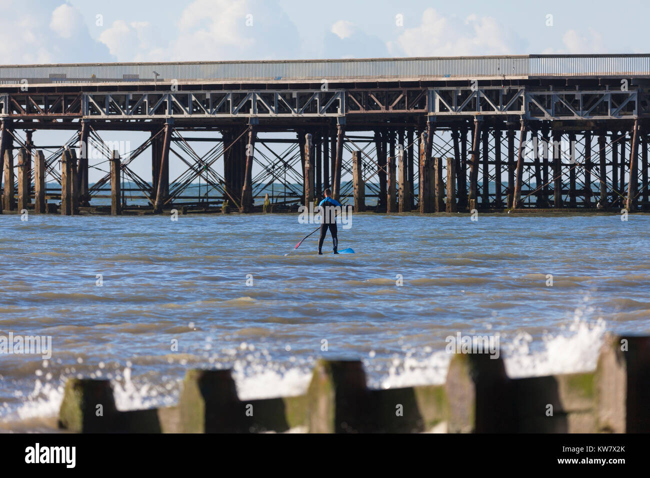 Ein Paddel boarder Paddle Boarding geht in der Nähe der Pier von Hastings einen genaueren Blick, East Sussex zu nehmen Stockfoto